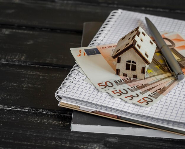 Foto bloc de notas de billetes en euros de la casa modelo sobre fondo de madera oscura el concepto de compra venta comercio