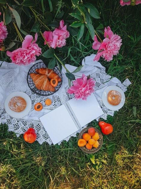 Bloc de notas en blanco para escribir, Picnic en estilo vintage con peonías rosas, Frutas y pan, Enfoque selectivo