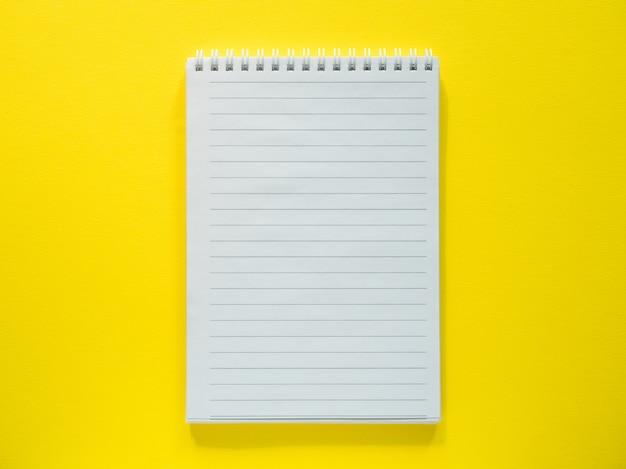 Bloc de notas para escribir en el escritorio amarillo, plano, espacio de copia.