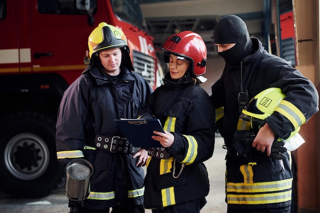 Con bloc de notas Grupo de bomberos con uniforme protector que está en la estación