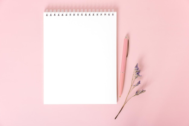 Bloc de notas con hojas blancas en blanco bolígrafo rosa y ramita de flores secas