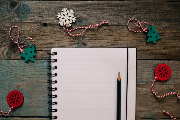 Bloc de notas y lápiz, decoración navideña de madera, año nuevo, marco plano de madera oscura.