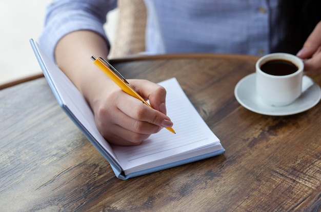 Bloc de notas de mano de mujer en cafe