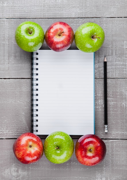 Bloc de notas con manzanas saludables como idea de plan de dieta en tablero de madera