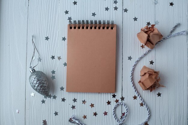 Un bloc de notas en una mesa de madera cerca del árbol de Navidad. Cuaderno para recordarme. Calendario festivo.