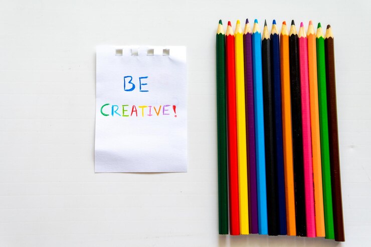 El bloc de notas con las palabras Sé creativo junto a los lápices de colores