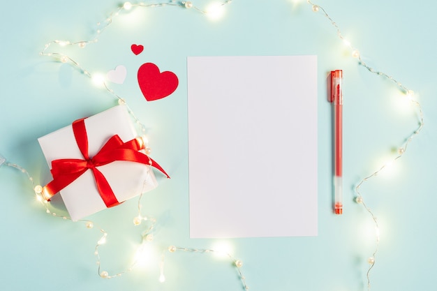 Bloc de notas de papel en blanco de escritorio. Plano de fondo de mesa de trabajo azul con regalo de San Valentín