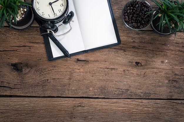 El bloc de notas y el reloj se colocan en una vista superior de la mesa de madera