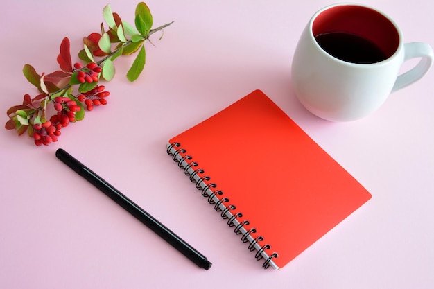 bloc de notas rojo aislado con taza de té y bolígrafo negro, primer plano