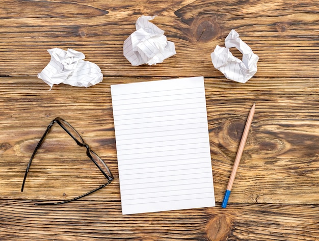 Foto bloc de notas con sábanas arrugadas y vasos en la mesa vista superior