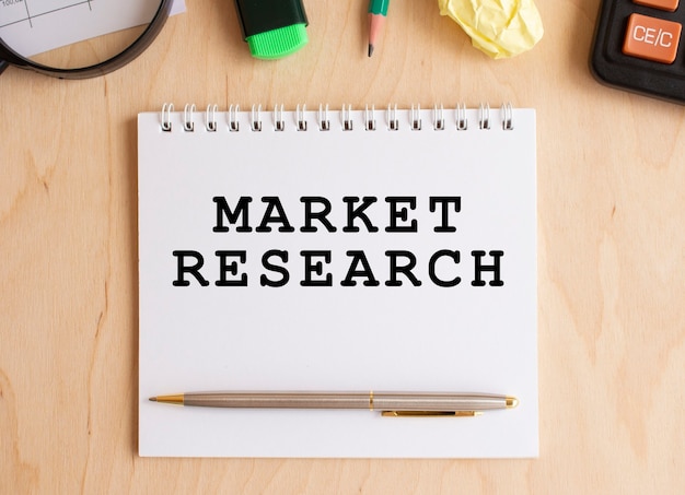 Bloc de notas con texto investigación de mercado en una mesa de madera, cerca de la calculadora y suministros de oficina. concepto de negocio.