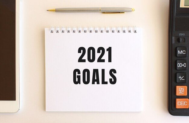Bloc de notas con el texto OBJETIVOS 2021 sobre un fondo blanco. Concepto de negocio.