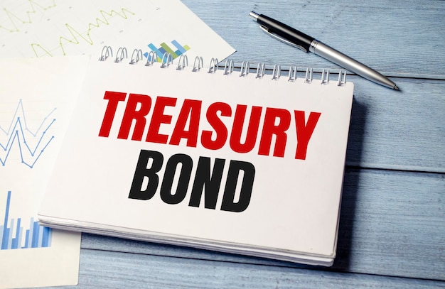 Bloc de notas con texto TREASURy BOND en gráficos comerciales y bolígrafos y gráficos