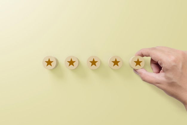 Foto bloco de madeira de mão com símbolo de cinco estrelas para aumentar a classificação da empresa com fundo amarelo