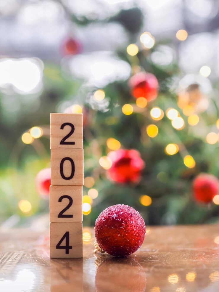 Foto bloco de madeira número 2024 e bola vermelha com fundo bokeh de luz de natal feliz natal e feliz ano novo 2024