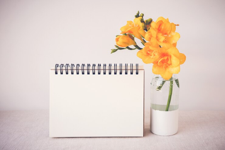 Foto bloco de notas com flores amarelas no vaso mock up