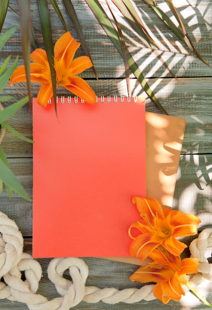 Foto bloco de notas com flores de lírio e sombras de palmeiras