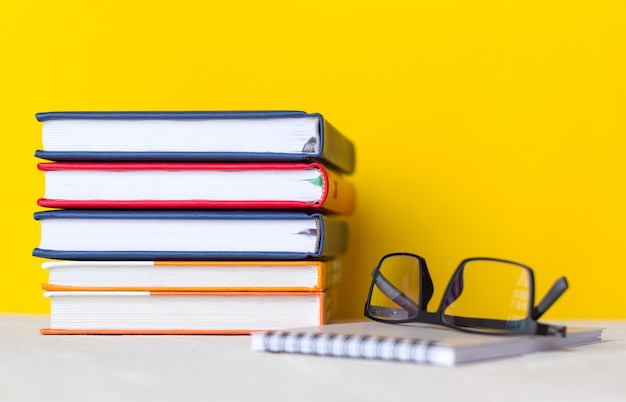 Bloco de notas de óculos uma pilha de livros sobre um fundo claro na mesa copie o espaço