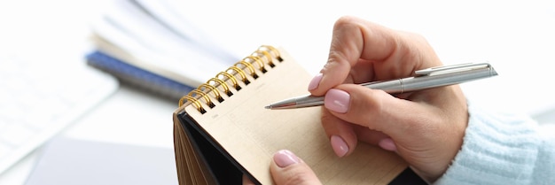 Bloco de notas em branco para escrever o planejamento do dia na mão feminina com o conceito de dia de planejamento de caneta