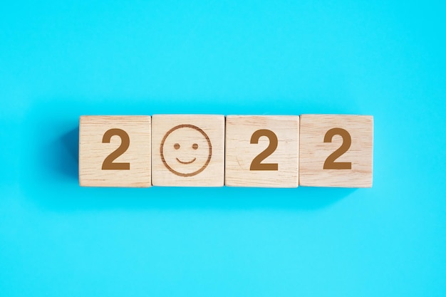 Bloco de rosto de sorriso com texto de 2022 em fundo azul. Conceitos de satisfação, feedback, revisão e ano novo