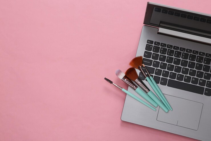 Foto blog de belleza en línea laptop con pinceles de maquillaje sobre fondo rosa vista superior