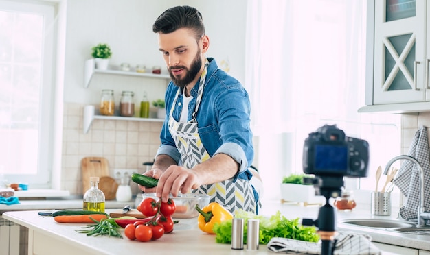 Foto blog de cocina de hombre real en casa mientras chico cocina ensalada vegana fresca y saludable