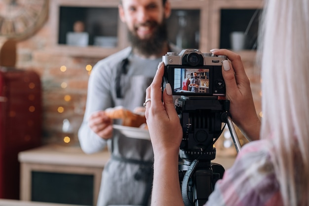 Blog culinario. Pasatiempo de cocinar alimentos. Video tutorial de grabación de pareja. Hombre en delantal. Mujer con cámara.