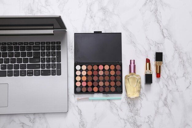 Blog de beleza online Laptop com acessórios de maquiagem na superfície de mármore Vista superior