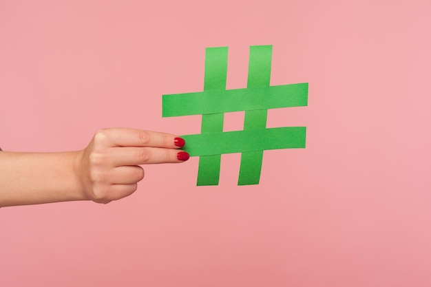 Blog marketing tendencias en redes sociales Primer plano de una mano femenina sosteniendo un cartel de hashtag verde que comparte un mensaje etiquetado famosa publicación en Internet que promueve contenido web e ideas virales tiro de estudio interior aislado