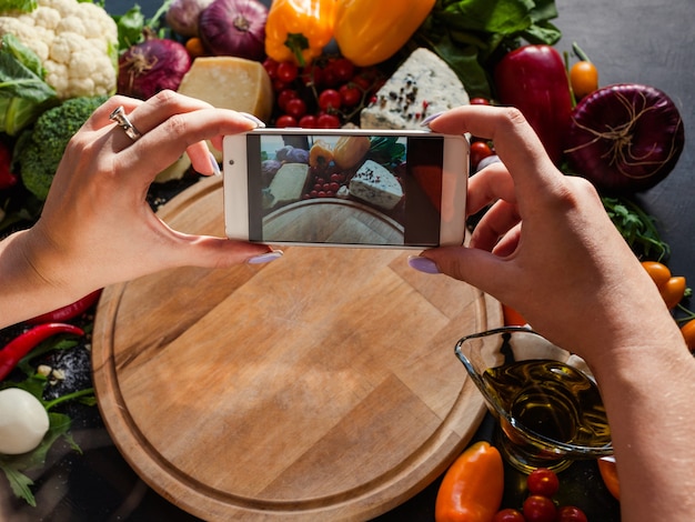 Blogger de alimentos tomando fotos en su teléfono inteligente. Blog de redes sociales concepto de tecnología moderna