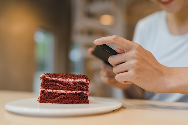 Blogger Asiatische freundliche Influencerin isst Kuchen im Nachtcafé