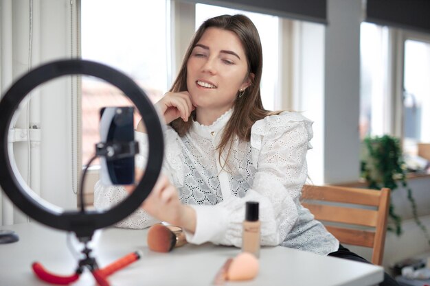 Blogger de belleza de estilo de vida que transmite en línea desde el estudio en casa diversa mujer milenaria que trabaja