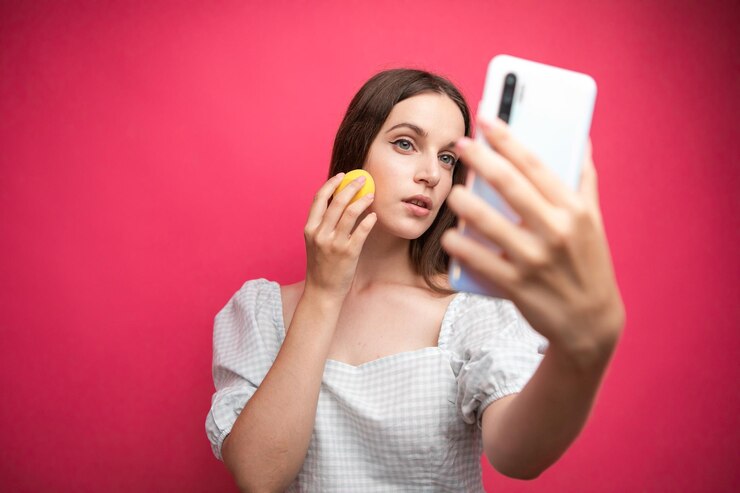 Blogger de belleza grabando tutorial de maquillaje sobre fondo rosa