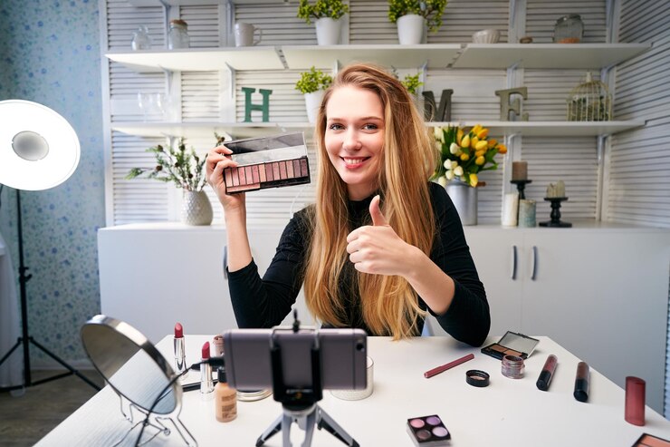 Foto blogger de belleza mujer filmando rutina de maquillaje diario tutorial cerca de la cámara en el trípode influencer chica transmisión en vivo revisión de productos cosméticos en el estudio en casa vlogger mujer mostrando la paleta de sombras para los ojos