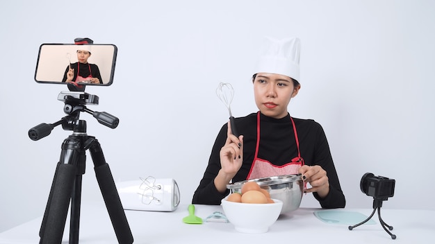 Blogger de comida transmitiendo en vivo. Chef mujer instructora de comida en línea. Cocinar con suscriptores a través de la cámara del teléfono en línea.