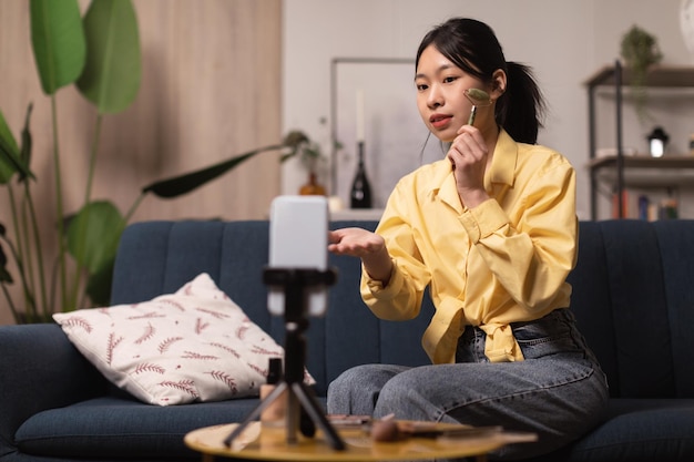 Blogger coreana dama haciendo masaje facial con rodillo de piedra interior