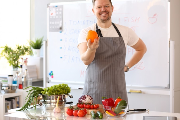 Blogger de homem segurando laranja cozinhar legumes