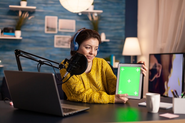 Blogger falando ao microfone segurando o bloco de notas com tela verde durante um podcast de entretenimento no ar ...