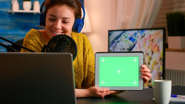Blogger falando ao microfone segurando o bloco de notas com tela verde durante um podcast de entretenimento
