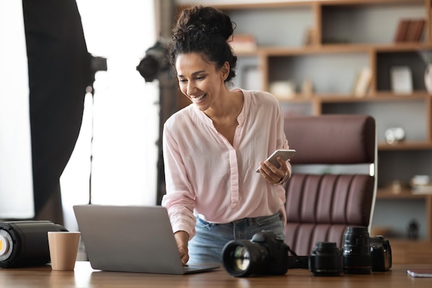 Foto blogger femenina creativa que trabaja desde casa usando varios dispositivos