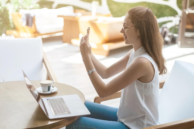 Blogger femenina tomando un selfie mientras está sentado en una mesa en un café