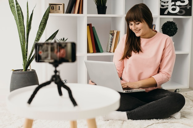 Blogger femenino streaming en casa con portátil y smartphone