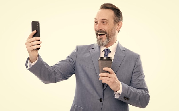 Blogger de hombre feliz en traje meking selfie en teléfono y beber café aislado en videollamada blanca