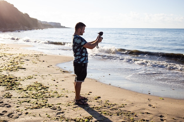 Blogger de hombre haciendo fotos en el mirador cerca del mar en la playa