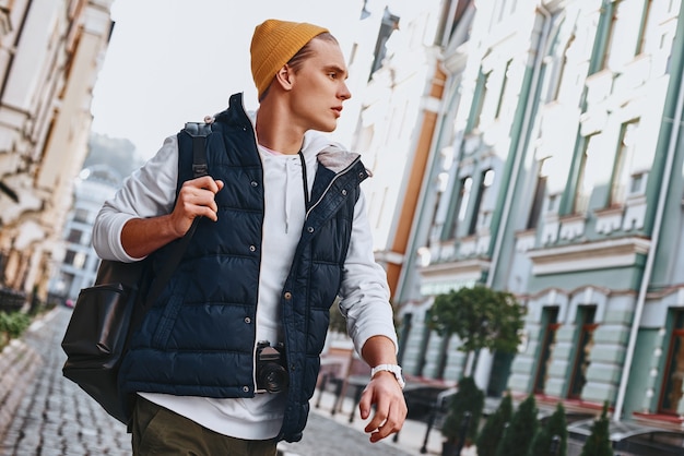 Blogger joven turista está caminando con la cámara en la ciudad vieja