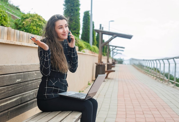 Blogger-Mädchen spricht auf dem Smartphone, indem sie ihre Hand im Park hebt