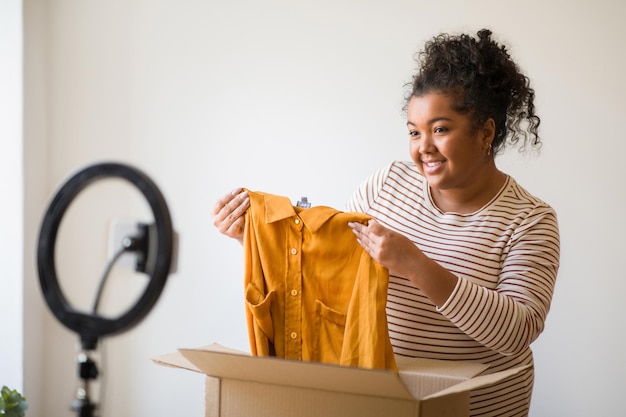 Blogger de moda de mujer gordita linda que muestra ropa de marca desempacando paquete