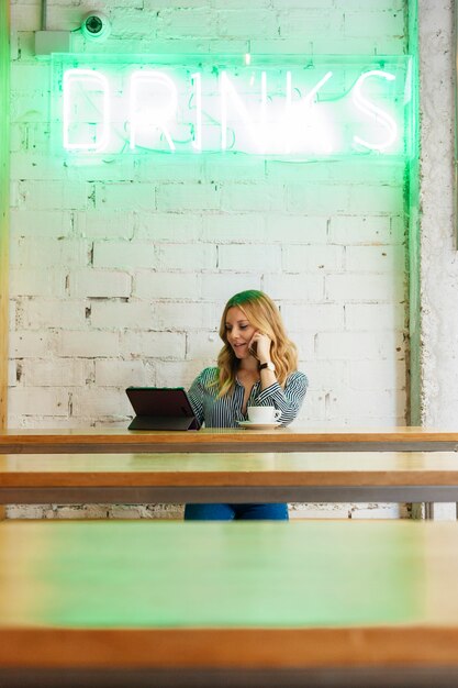 Blogger mujer trabajando con tecnología en una cafetería moderna