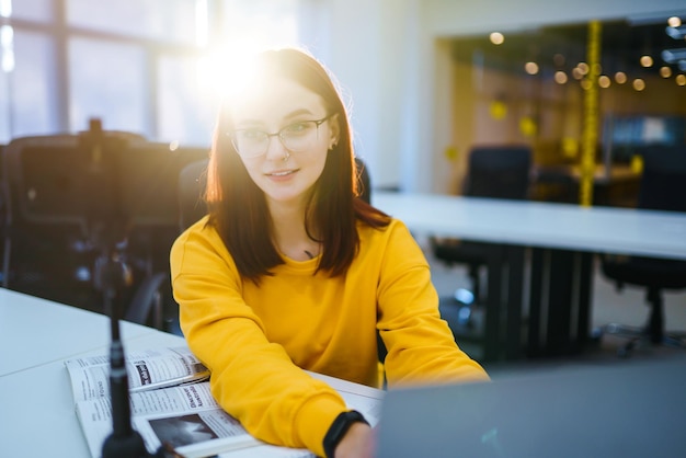 Bloggerin mit Laptop, die Videos aufzeichnet, während sie im Büro sitzt und über Startup-Unternehmen spricht