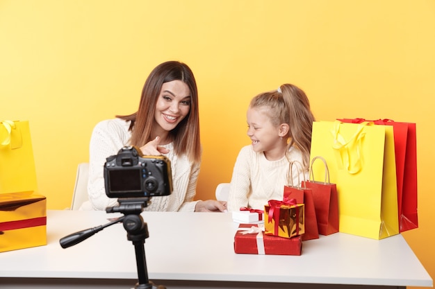 Bloggerin und kleines Mädchen, die Video vor der Kamera zusammen aufnehmen, sitzen im Studio